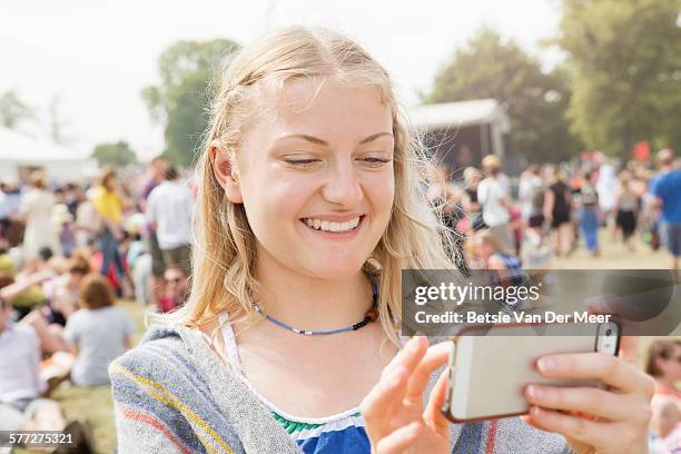 woman looks at mobile phone at music festival - festivaleiro - fotografias e filmes do acervo