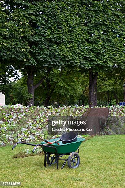 wheelbarrow in a city park with flowers - jardinage stock pictures, royalty-free photos & images
