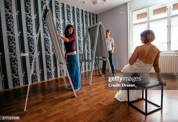 model posing in european studio to two female artists - artists model stock pictures, royalty-free photos & images