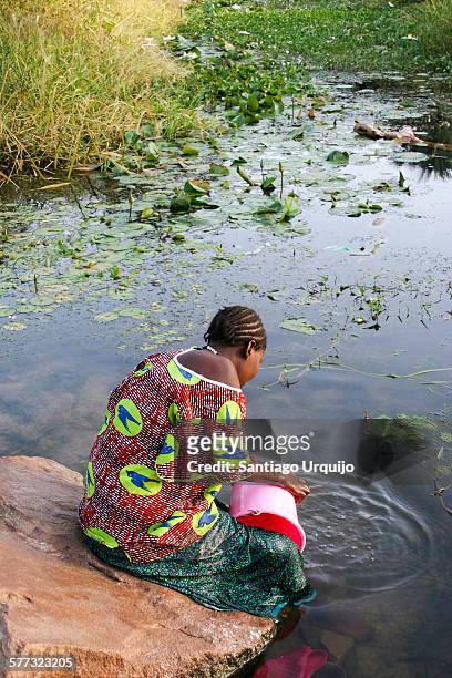 woman doing the laundry on a pond - mali imagens e fotografias de stock