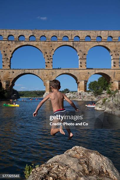 child (6 years) jumping into the river - boy barefoot rear view stock-fotos und bilder