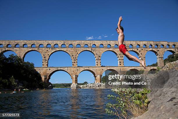 child (10 years) jumping into the river - pont du gard aqueduct stock pictures, royalty-free photos & images