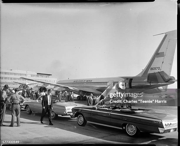 View of people, including several police officers, gathered around cars parked beside Air Force One airplane on the tarmac at Allegheny County...