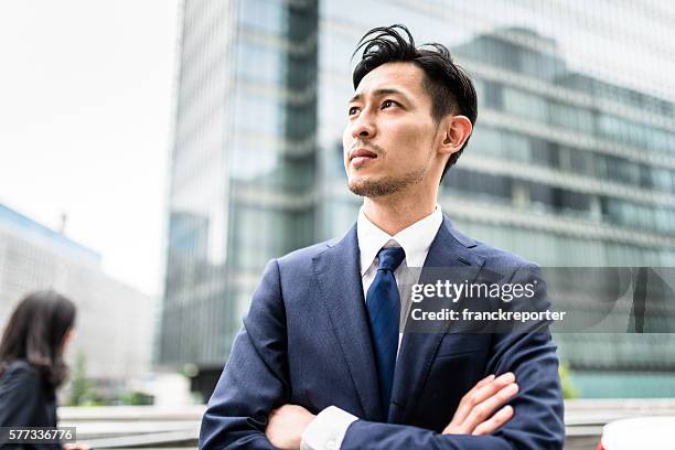 腕を組んで立っているビジ�ネス日本人 - man looking away ストックフォトと画像