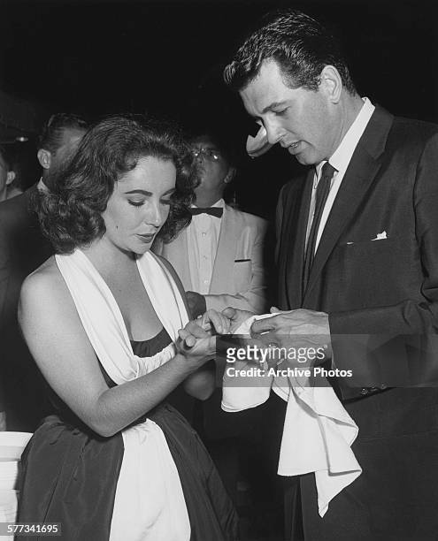 American actor Rock Hudson dries the hands of actress Elizabeth Taylor after a handprint and footprint ceremony at Grauman's Chinese Theatre in Los...