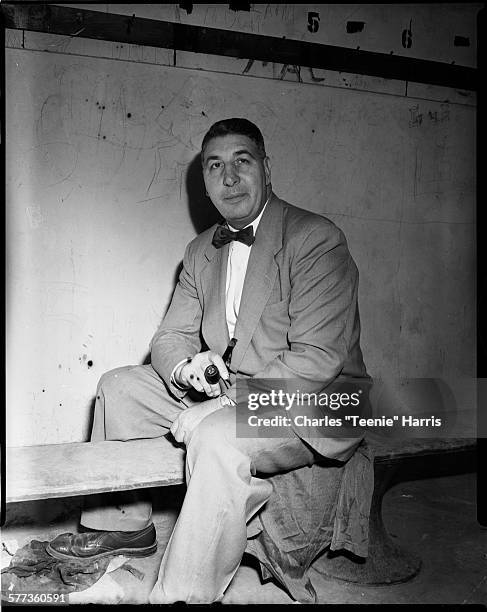 Portrait of Westinghouse High School football coach Pete Dimperio seated on bench, in interior with light colored wall with graffiti, some which...