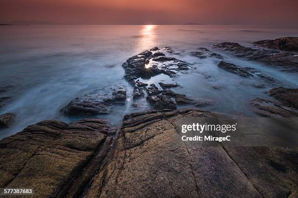 rock on beach with flowing water waves sunlight - 2be3 stock pictures, royalty-free photos & images