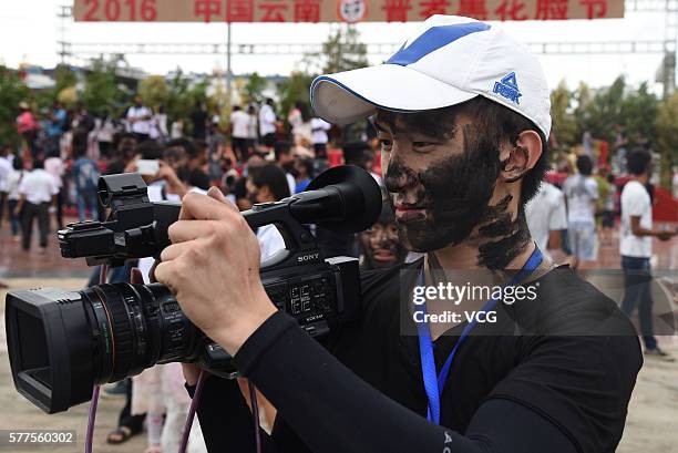 Photographer is daubed rice ash on face during the Face Painting Festival in Puzhehei Resort of Qiubei County on July 18, 2016 in Wenshan Prefecture,...