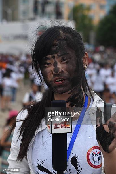 Girl who is daubed rice ash on face receives an interview during the Face Painting Festival in Puzhehei Resort of Qiubei County on July 18, 2016 in...