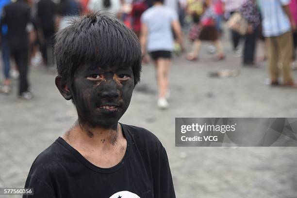 Child is daubed rice ash on face during the Face Painting Festival in Puzhehei Resort of Qiubei County on July 18, 2016 in Wenshan Prefecture, Yunnan...