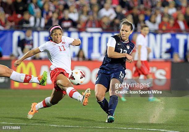 January 2014 - U.S. Women's National Team midfielder Lauren Holiday takes a shot as Canada midfielder Desiree Scott defends during the international...