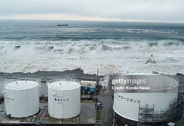 Okuma, Japan - Handout photo shows tsunami, triggered by a powerful earthquake, approaching fuel oil tanks of the No. 5 reactor at the Fukushima...