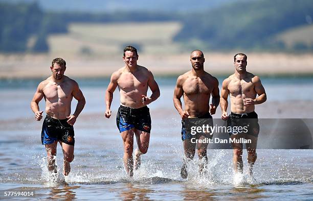 Matt Jess, Tom Johnson, Olly Woodburn and Haydn Thomas of Exeter Chiefs run through the water during a training session on Exmouth Beach on July 19,...