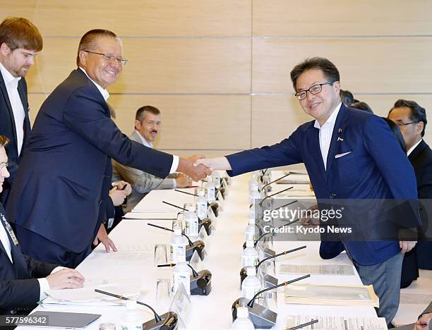 Russian Economic Development Minister Alexey Ulyukaev and Japanese Deputy Chief Cabinet Secretary Hiroshige Seko shake hands prior to their talks at...