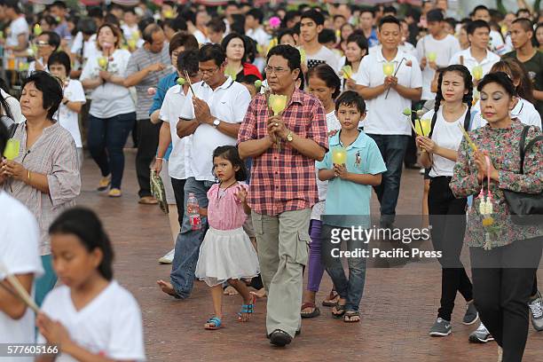 People pray while holding candles as they walk around the Phra Si Sakkaya Thotsaphala Yan Prathan Phutthamonthon Suthat during Asalha Puja Day at...