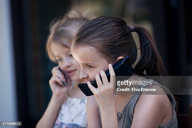 two girls (8-11) talking on cell phones - feature phone stockfoto's en -beelden