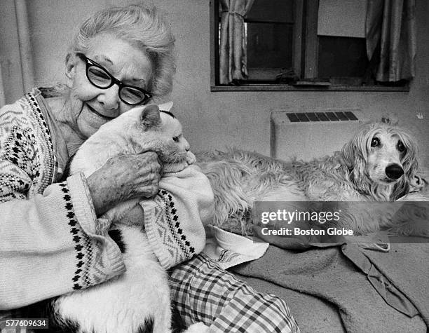 Alice Stacy hugs her cat Mischief, as her Afghan dog Good Boy sits beside her at the Columbia Point housing project in Dorchester on Feb. 25, 1988....