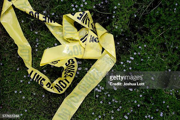 Yellow police crime scene tape rests in the grass on July 19, 2016 in Baton Rouge, Louisiana. The crime scene tape lays in the area where three...
