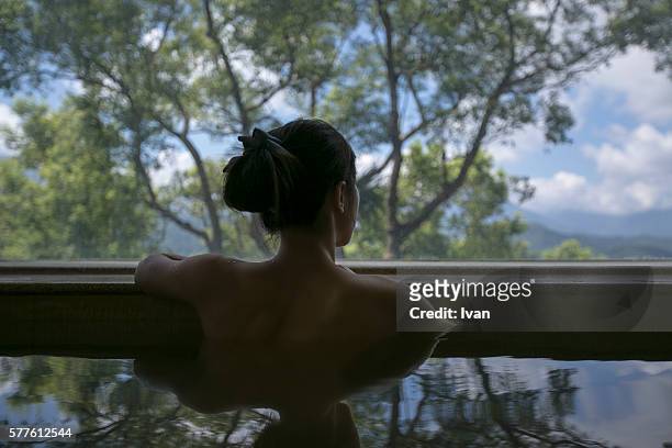 a young woman enjoying the japanese style hot spring waters with beautiful landscape view - japanese culture stockfoto's en -beelden