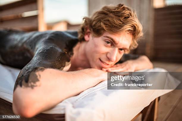 man relaxing on a mud therapy at spa - mud therapy stock pictures, royalty-free photos & images