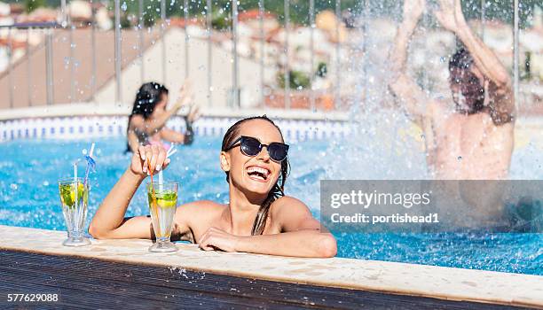 smiling young woman drinking cocktails at swimming pool - rooftop pool stock pictures, royalty-free photos & images