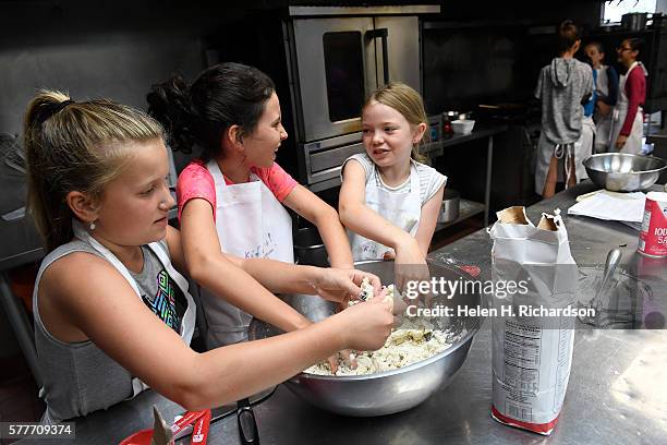 Sofia Leinbach left, Calyx Klein and Madison McCulloch right, use their hands to mix masa harina to make homemade corn tortillas during a Kids Cook...