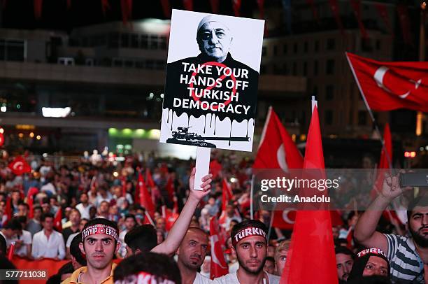 Man holds a placard reading in "Take your hands of Turkish democracy" with the portrait of Fethullah Gulen in front of Turkish President Recep Tayyip...