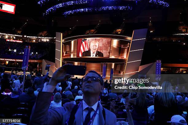 Delegates watch Republican presidential candidate Donald Trump speak on a screen from New York City, on the second day of the Republican National...