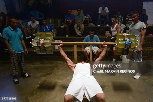 Member of the MS-13 gang uses bottles with water as makeshift dumbbells to lift weight during a break in his studies at the Apanteos prison, in Santa...