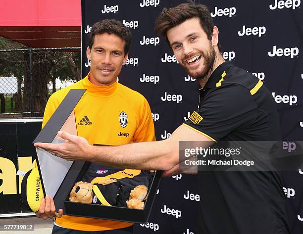 Trent Cotchin of the Tigers presents a gift to Hernanes of Juventus during a Richmond Tigers AFL and Juventus FC media opportunity at Punt Road Oval...