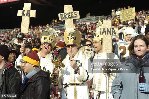 Three Saints fans dressed as Saints / Popes /Bishops hold a sign that says 'La-Brees-iana'. The New Orleans Saints defeated the Washington Redskins...