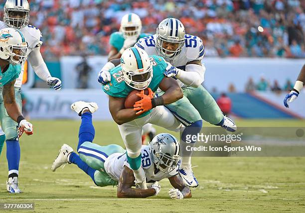 Dallas Cowboys linebacker Anthony Hitchens and defensive back Brandon Carr tackle Miami Dolphins running back Knowshon Moreno in Miami's 25-20...