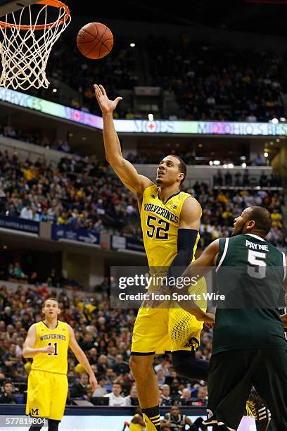 Michigan foward Jordan Morgan with the lay up around Michigan State center Adreian Payne during the Big Ten Championship basketball game between the...