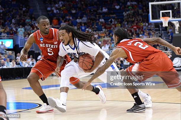 Jordair Jett of the Saint Louis Billikens tries to dribble between G Desmond Lee and G Anthony 'Cat' Barber of the NC State Wolfpack during the NC...