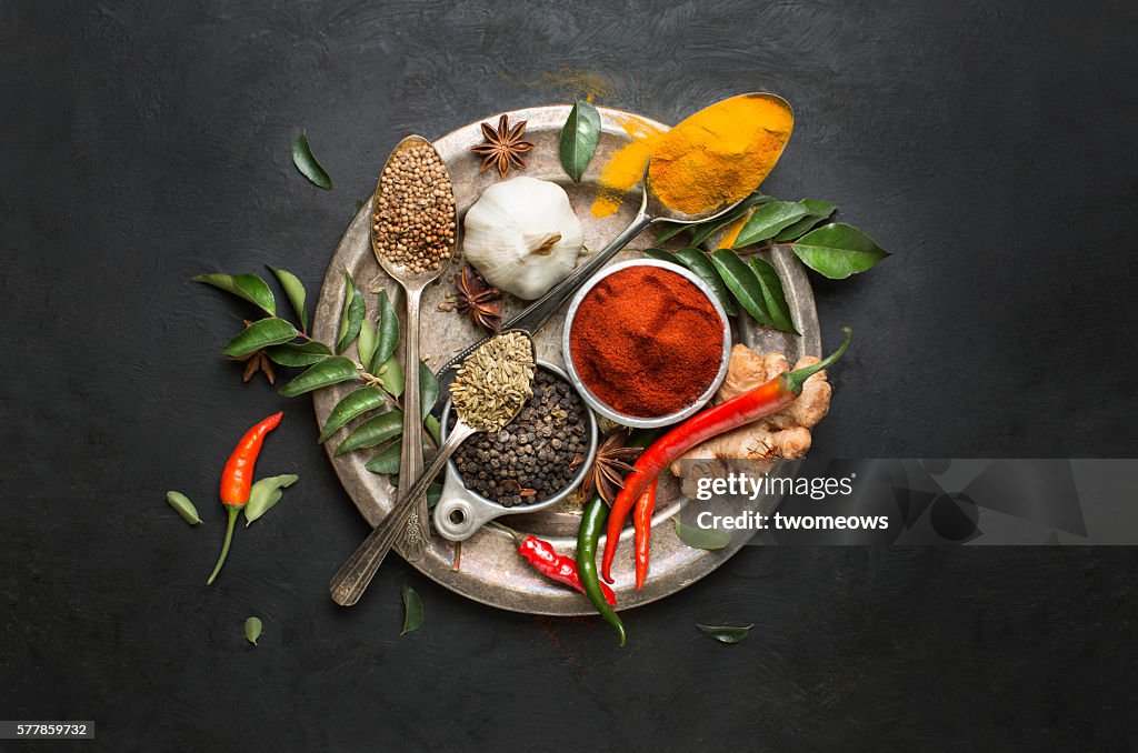 Flat lay overhead view herb and spices on textured black background.