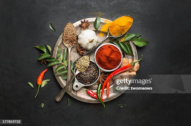 flat lay overhead view herb and spices on textured black background. - curry stock-fotos und bilder