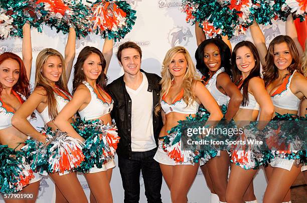 American Idol winner Kris Allen poses with the Miami Dolphin cheerleaders on the the orange carpet before the start of the NFL game between the...