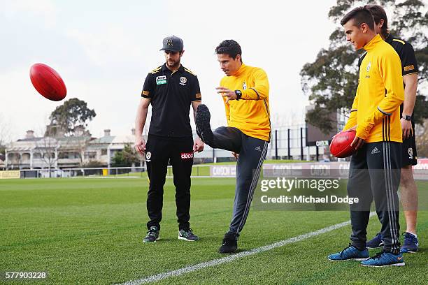 Trent Cotchin and Ivan Maric of the Tigers watch Hernanes kick a ball next to teammate Paulo Dybala of Juventus during a Richmond Tigers AFL and...