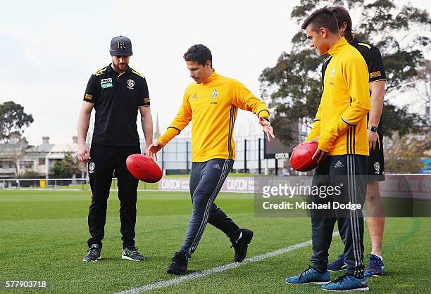 Trent Cotchin and Ivan Maric of the Tigers watch Hernanes kick a ball next to teammate Paulo Dybala of Juventus during a Richmond Tigers AFL and...