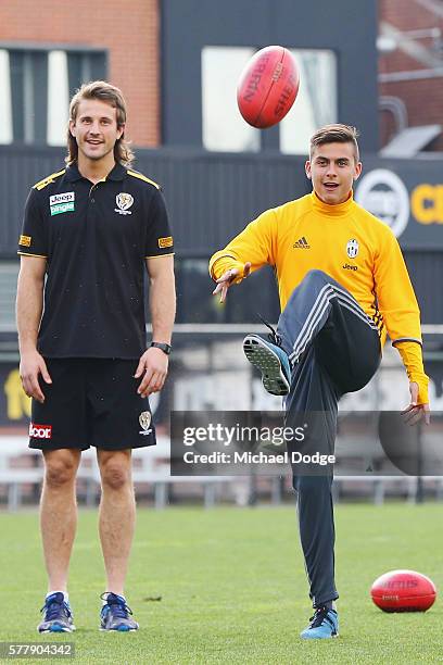 Ivan Maric of the Tigers watches Paulo Dybala kick an AFL fottball during a Richmond Tigers AFL and Juventus FC media opportunity at Punt Road Oval...