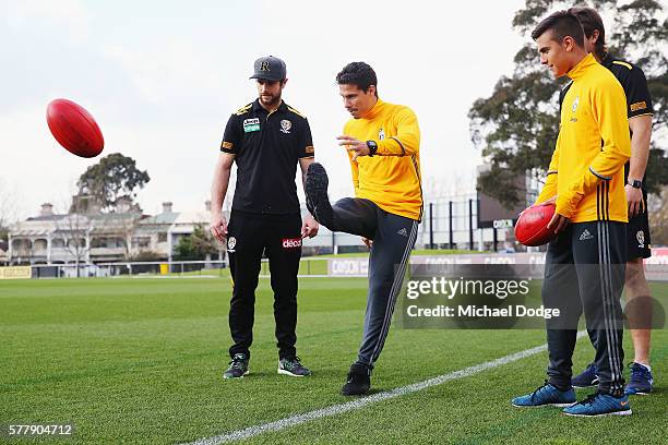 Trent Cotchin and Ivan Maric of the Tigers watch Hernanes kick a ball next to teammate Paulo Dybala of Juventus during a Richmond Tigers AFL and...