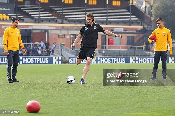 Ivan Maric of the Tigers kicks a soccer ball between Hernanes and Paulo Dybala of Juventus during a Richmond Tigers AFL and Juventus FC media...