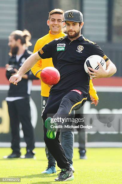 Trent Cotchin of the Tigers performs some soccer tricks with an AFL football in front of Paulo Dybala of Juventus during a Richmond Tigers AFL and...