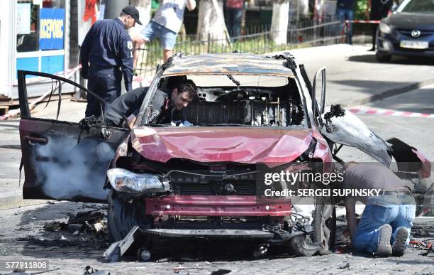 Ukrainian police officers and security services experts examine the charred car of journalist Pavel Sheremet, after he was killed in a car bomb in...