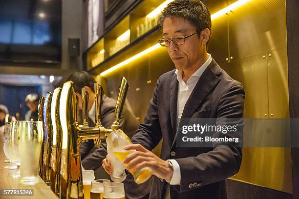 Bartender pours glasses of Suntory Holdings Ltd.'s The Premium Malt's Pilsner beer at the company's Master House bar in Hong Kong, China, on...