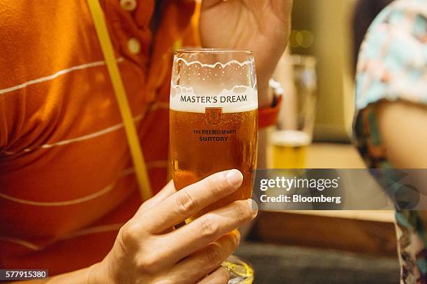 Member of the media holds a glass of Suntory Holdings Ltd.'s The Premium Malt's Master's Dream beer at the company's Master House bar in Hong Kong,...