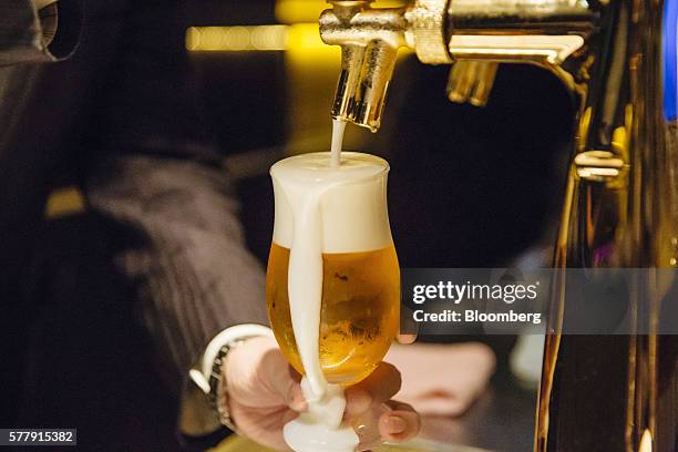 Foam spills over as a bartender pours a glass of Suntory Holdings Ltd.'s The Premium Malt's Ale beer at the company's Master House bar in Hong Kong,...