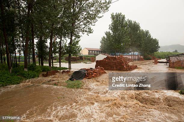 Flood waters tear through a village on July 19, 2016 at Linzhou, Henan Province, China. Torrential rain has caused severe flooding in Northern China,...