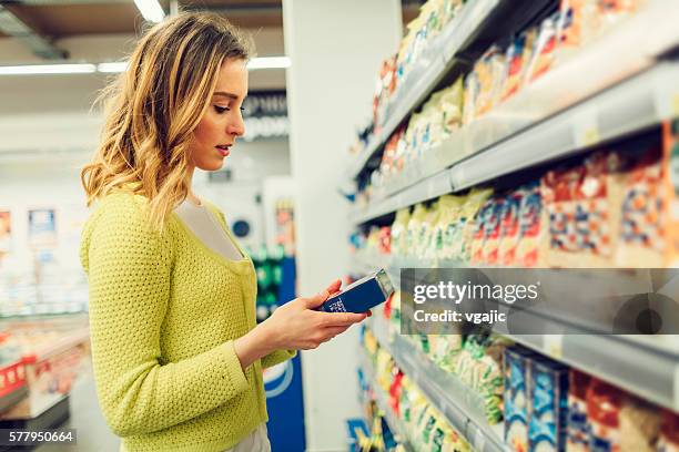 mujer joven en el supermercado compras de comestibles locales. - labels fotografías e imágenes de stock