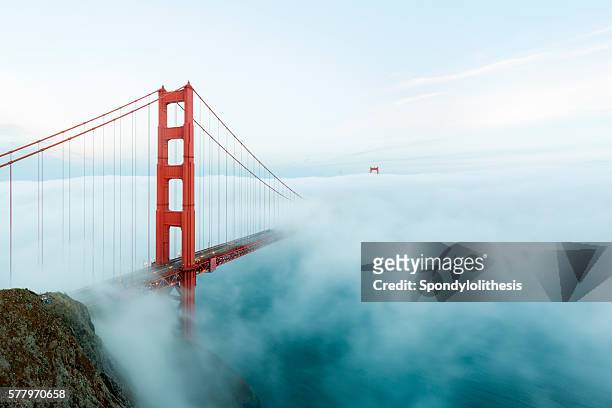 golden gate bridge with low fog, san francisco - san francisco californië stockfoto's en -beelden